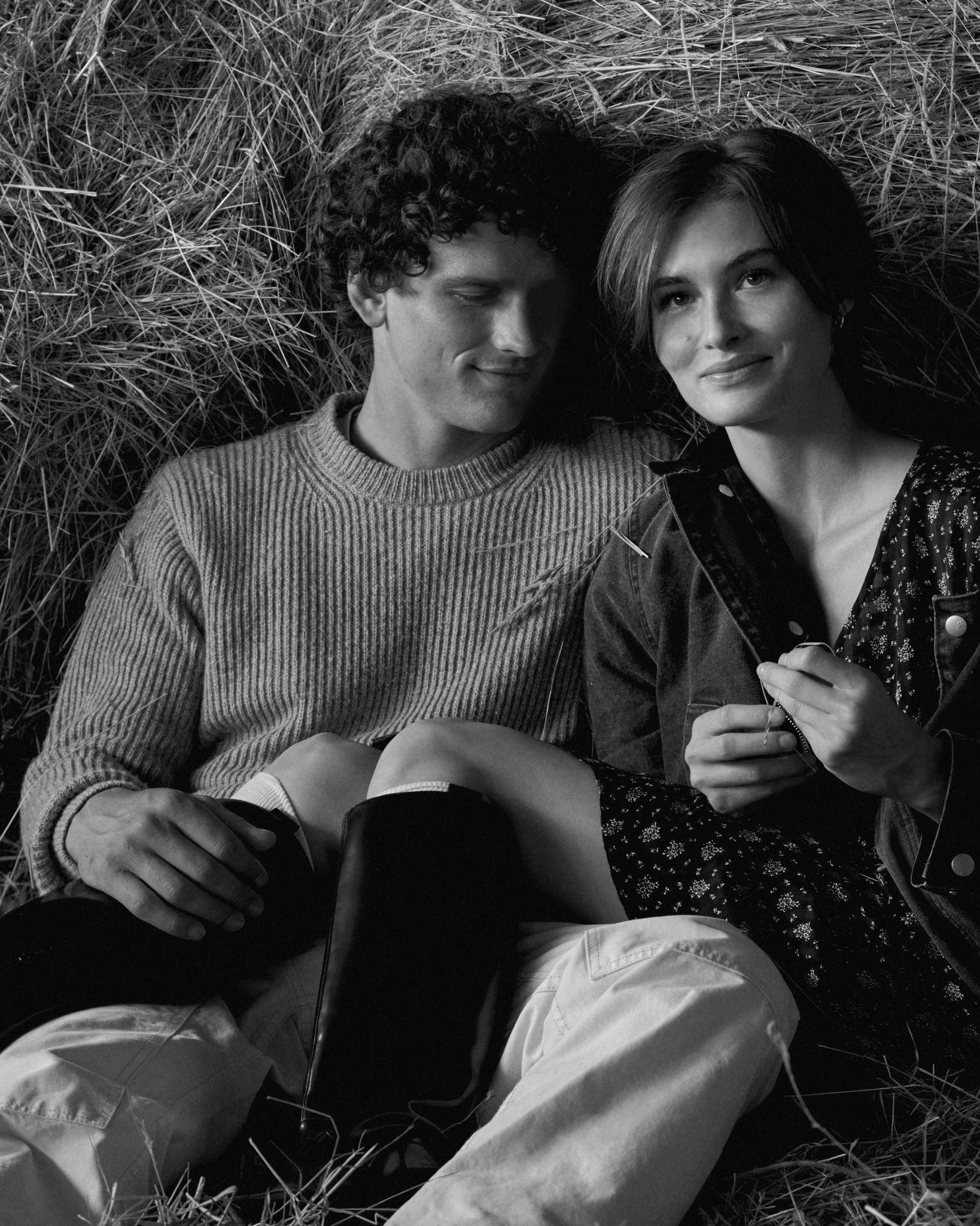 Black-and-white portrait of couple lying in hay