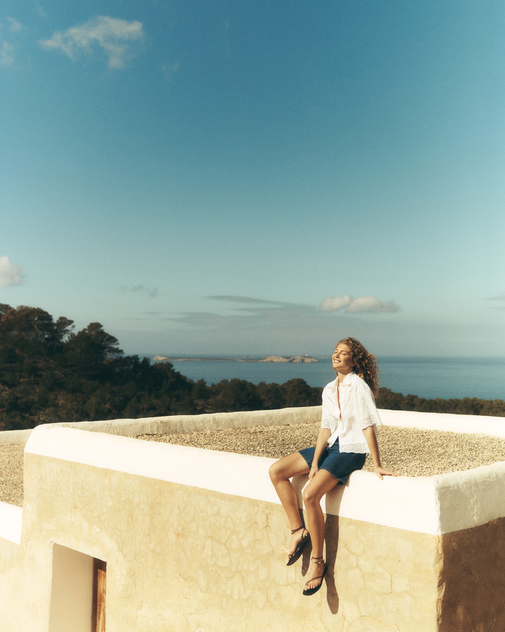 Woman sitting against blue sky